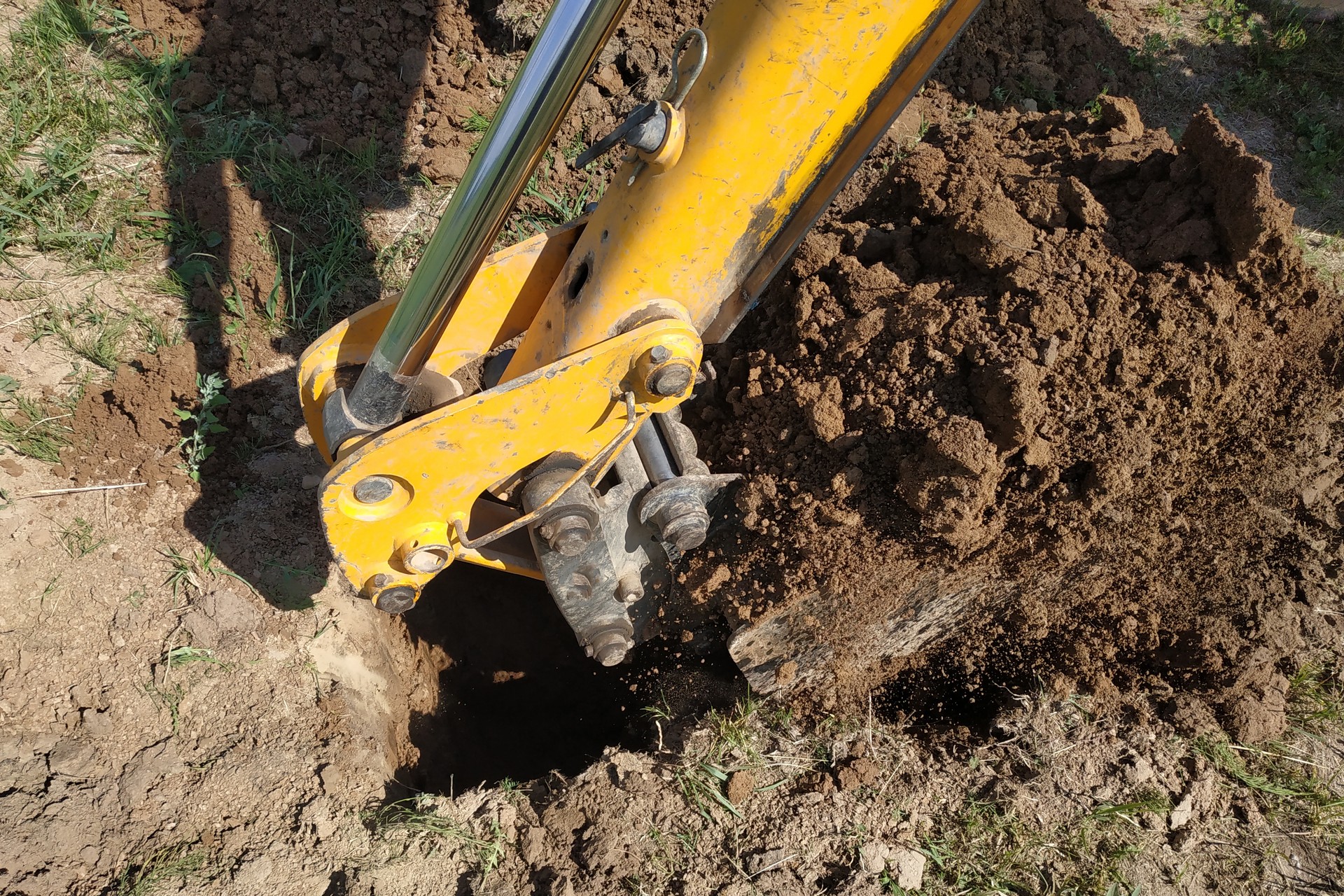 The yellow excavator digs a trench, construction works by means of automobile equipment.